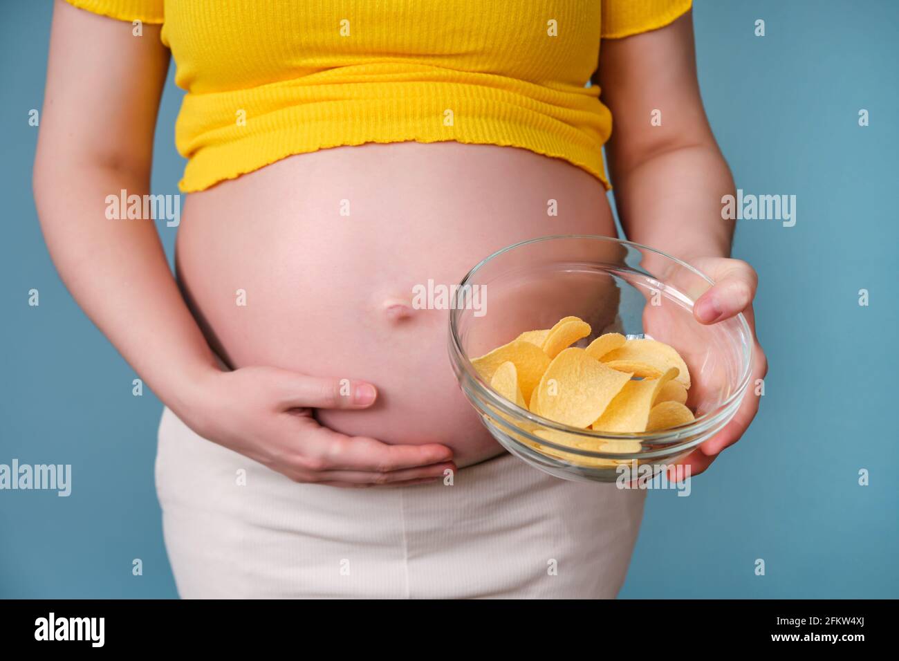 A pregnant woman holds a plate of chips in her hand Stock Photo Alamy