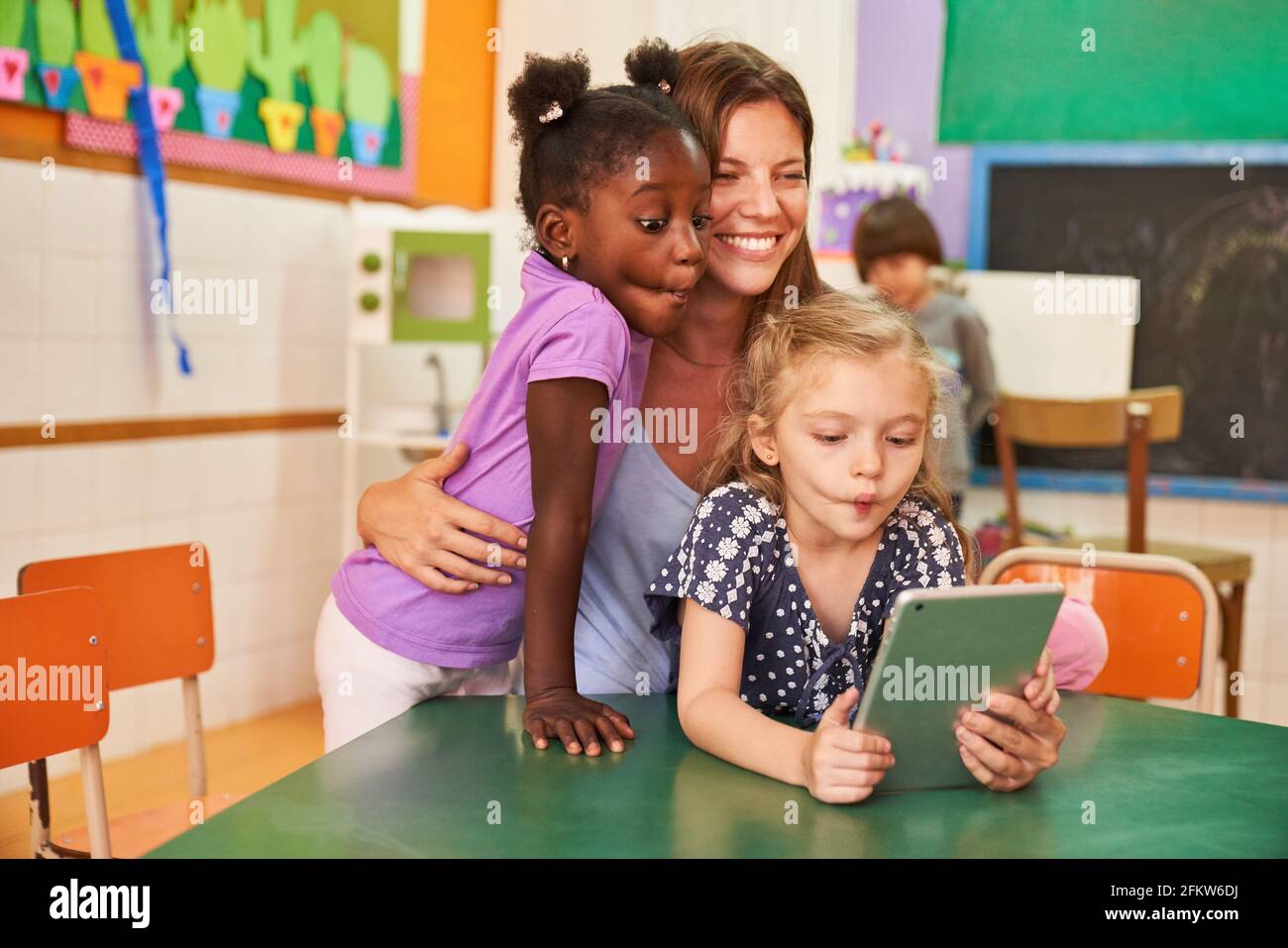 Children make a grimace on the tablet computer for selfie and social media in kindergarten Stock Photo