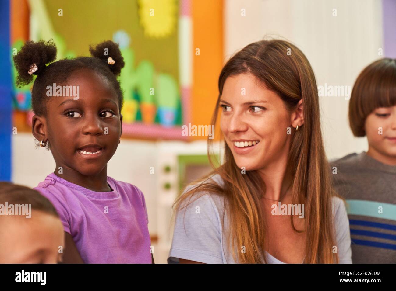Childminder or kindergarten teacher and African girl in kindergarten or after-school care center Stock Photo