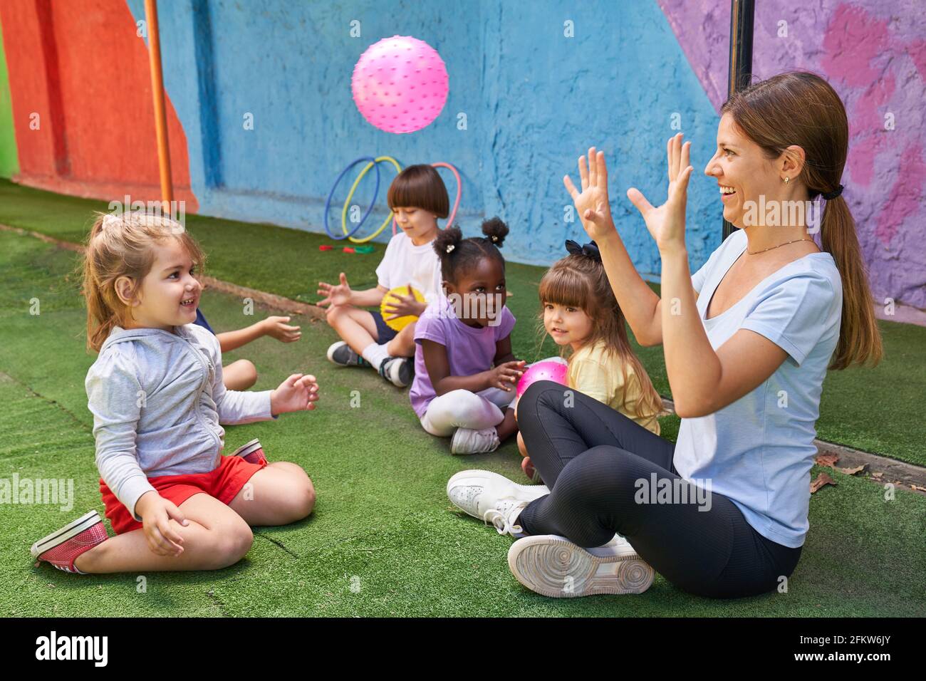 Children play ball together with the gym teacher in the international kindergarten Stock Photo
