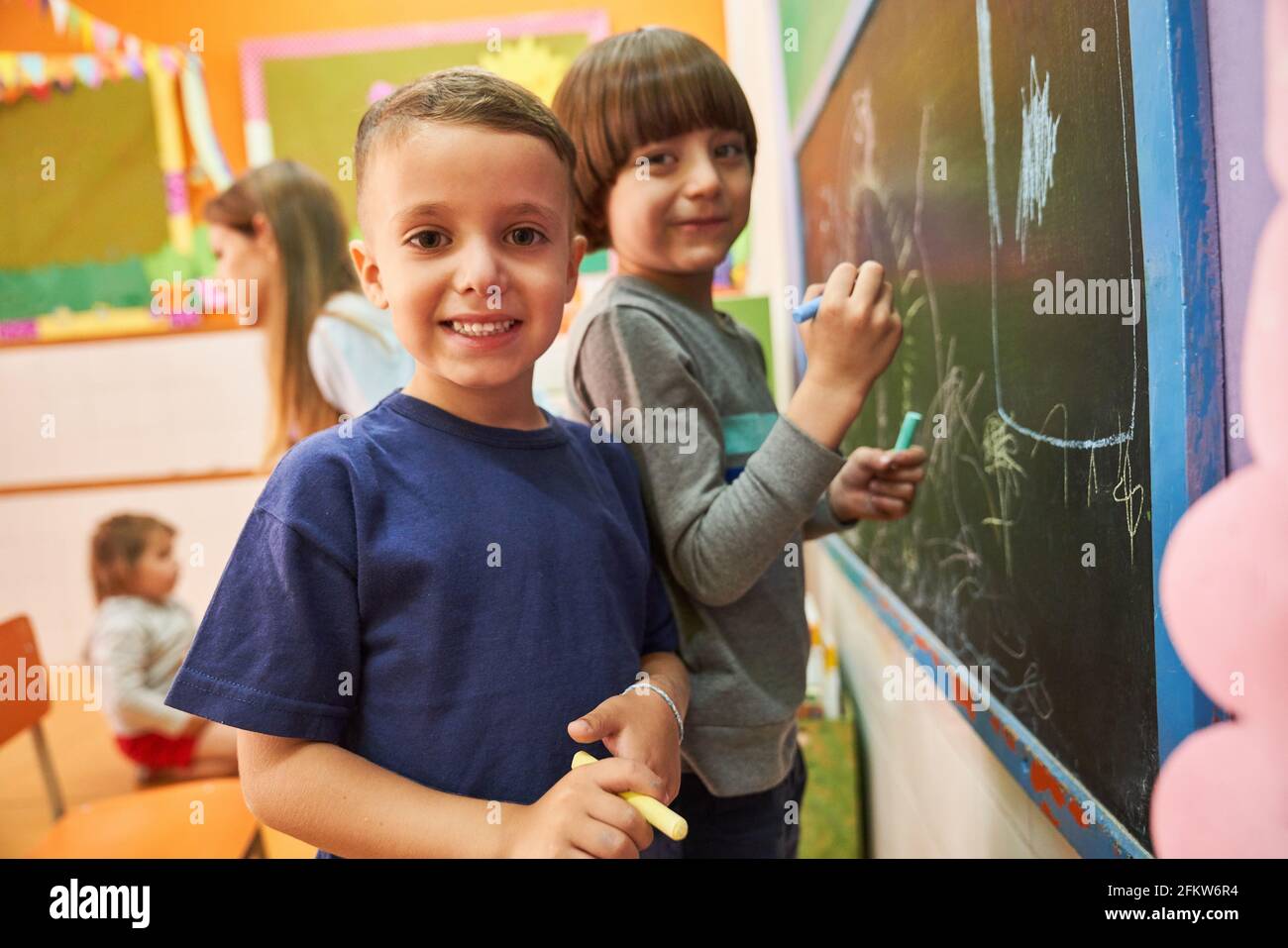 Children paint with chalk on the blackboard in preschool or elementary school in creative painting class Stock Photo