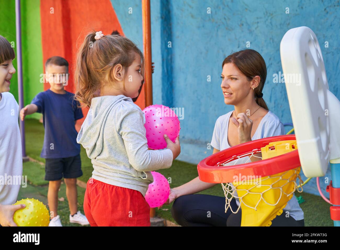 Sports teacher and children playing ball in sports class in daycare or preschool Stock Photo