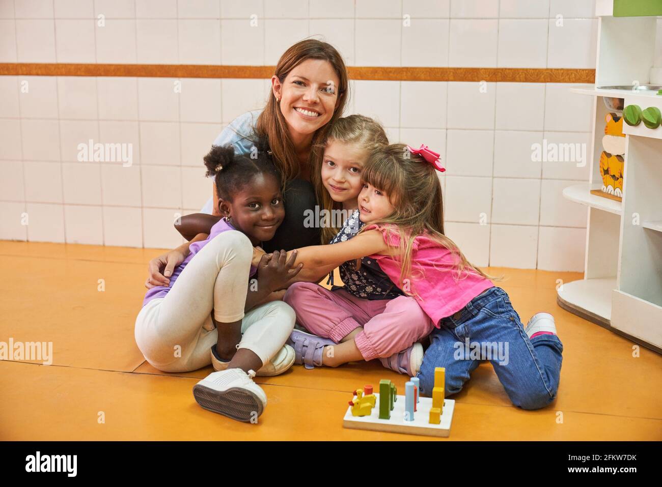 Childminders and multicultural children as friends in international after-school care centers or kindergartens Stock Photo