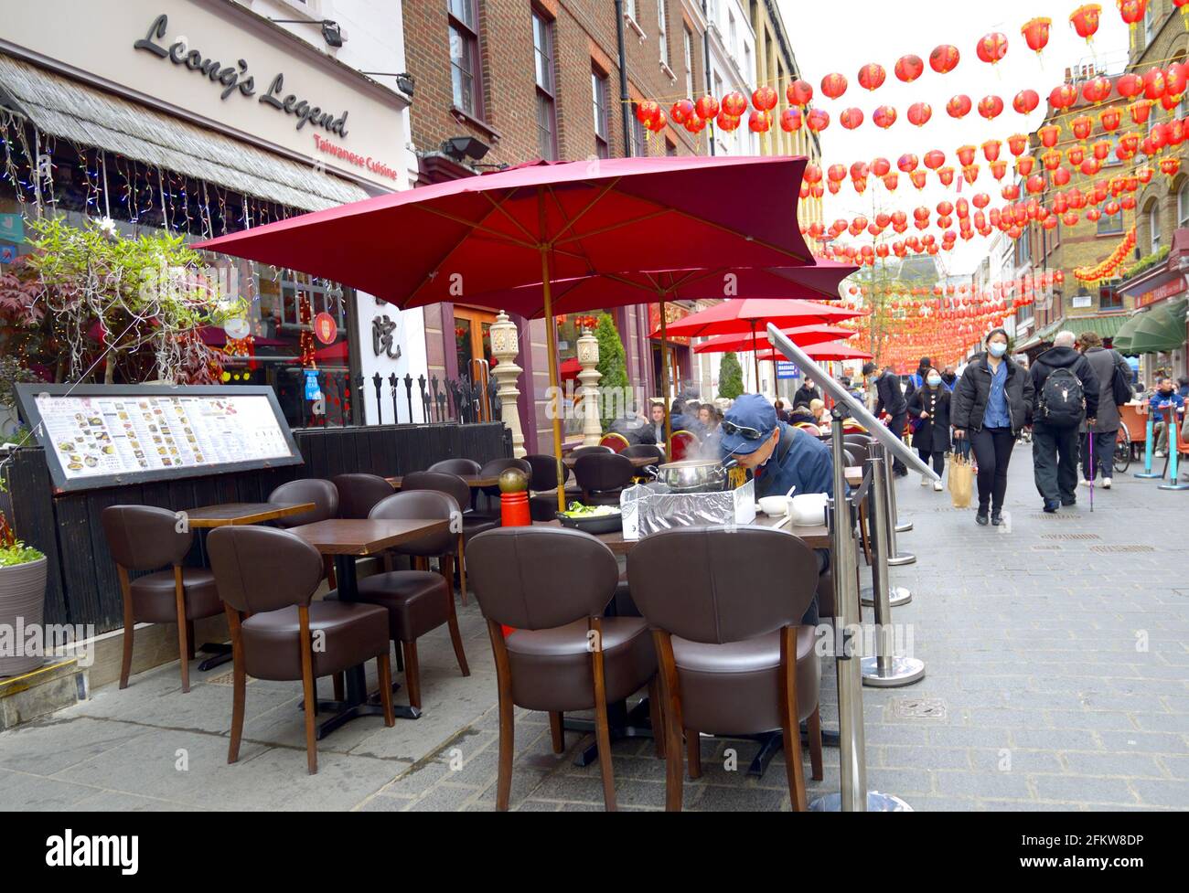 London, England, UK. Chinatown - Chinese man eating noodles in Gerrard Street Stock Photo