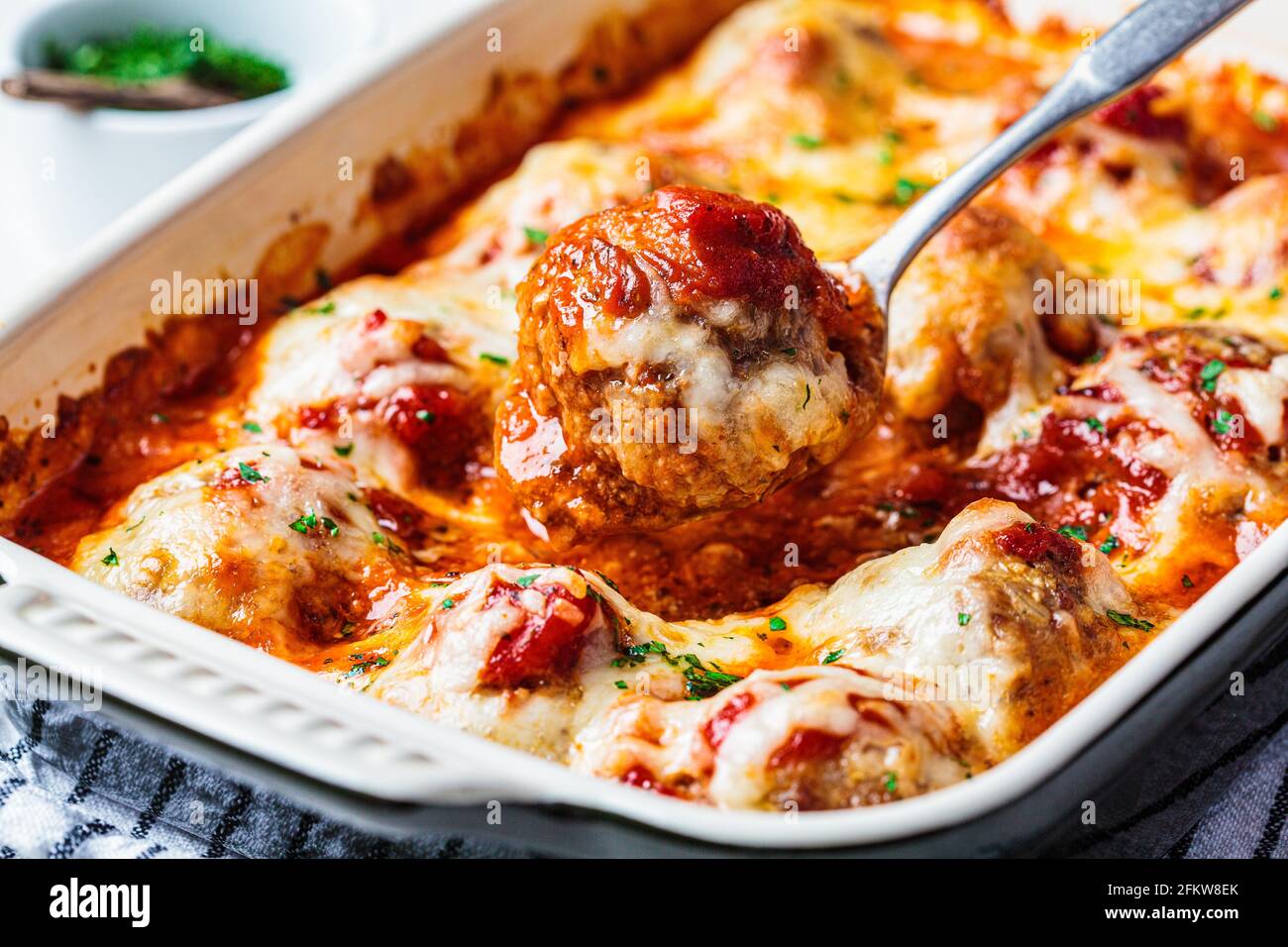 Baked cheesy meatballs casserole with tomato sauce in the oven dish