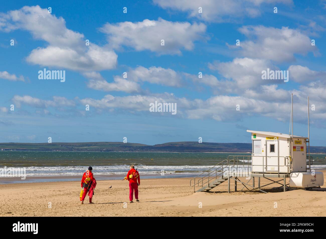 Bournemouth, Dorset UK. 4th May 2021. UK weather: after a stormy night the sun returns for a windy and sunny morning at Bournemouth beach, as few visitors head to the seaside. RNLI Lifeguards walk along the beach to the Lifeguard kiosk ready to keep a look out in the rough conditions.  Credit: Carolyn Jenkins/Alamy Live News Stock Photo