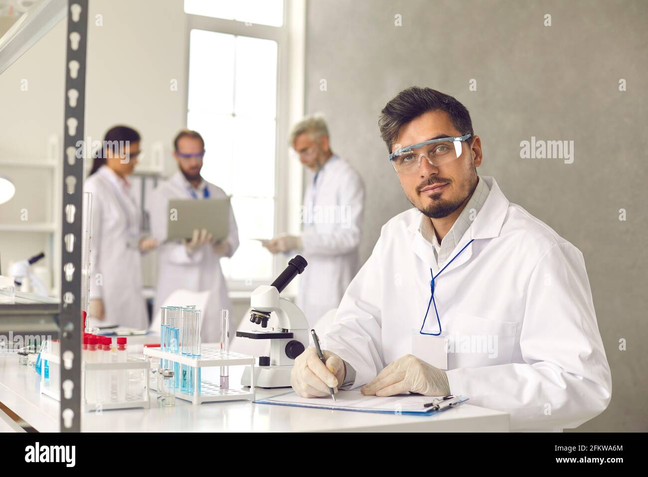 Portrait of man scientist working at laboratory making experiment conclusion Stock Photo
