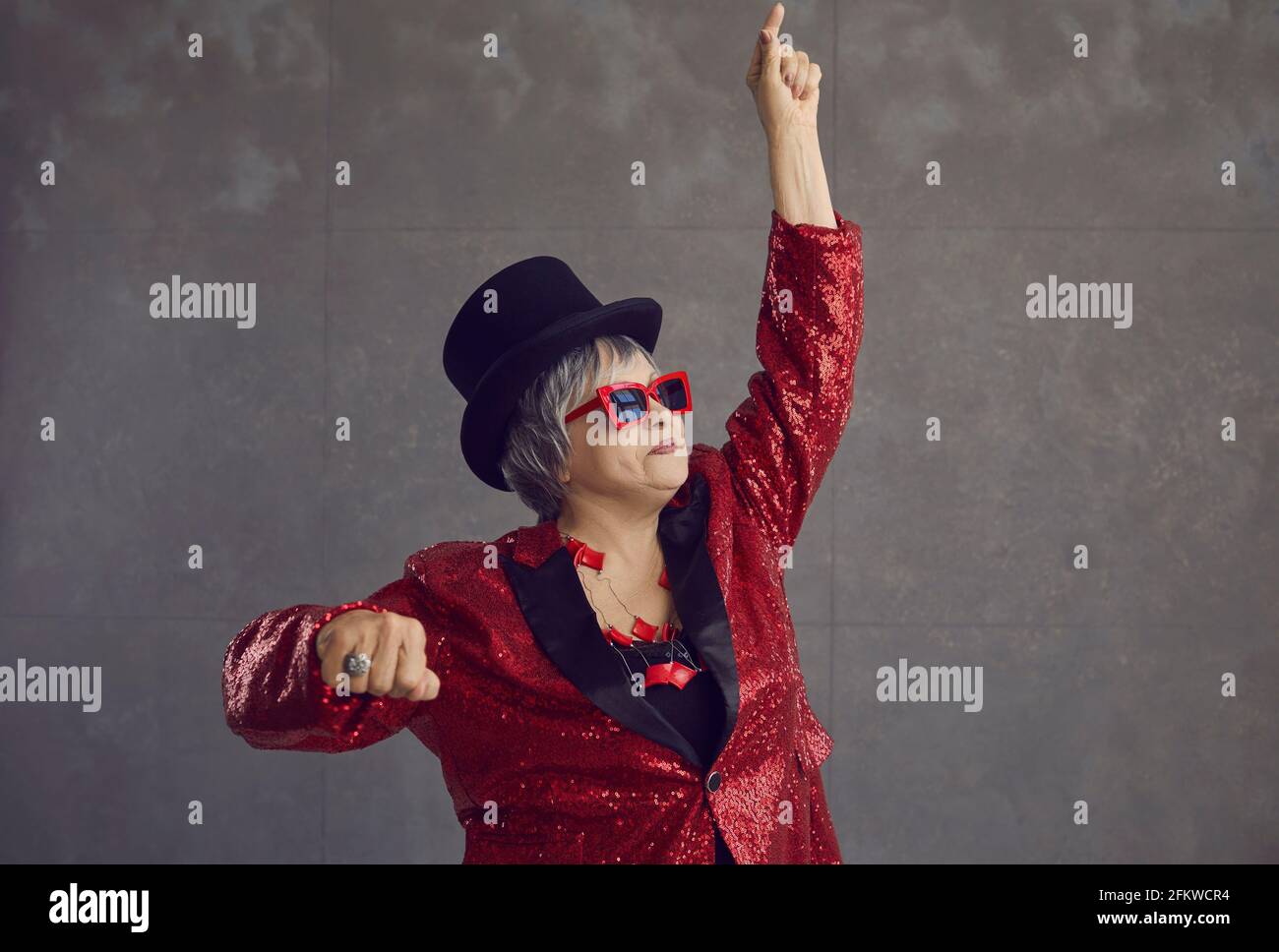 Funny senior woman in a party jacket dancing, having fun and feeling free and happy Stock Photo