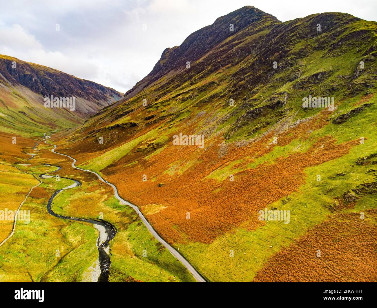 Aerial view of Honister Pass, a mountain pass with a road winding along Gatesgarthdale Beck mountain stream. One of the steepest and highest passes in Stock Photo