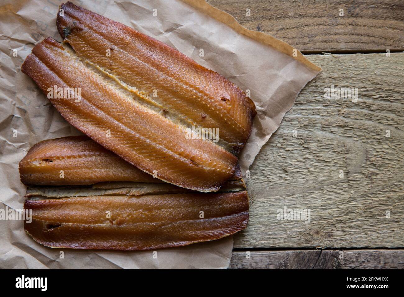 Smoked Craster kipper cutlets presented on a wooden background. Kippers are smoked herrings and are rich in fish oils. England UK GB Stock Photo