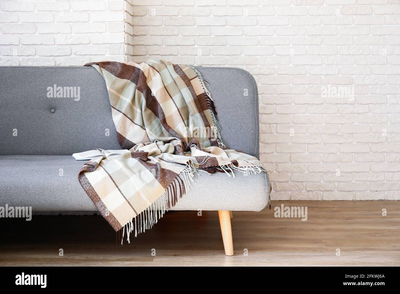 Minimalistic interior design concept. Grey textile sofa in spacious room of loft style apartment with wood textured laminated flooring. Background, co Stock Photo