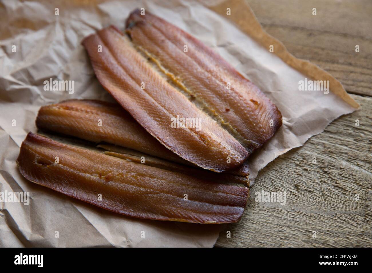 Smoked Craster kipper cutlets presented on a wooden background. Kippers are smoked herrings and are rich in fish oils. England UK GB Stock Photo