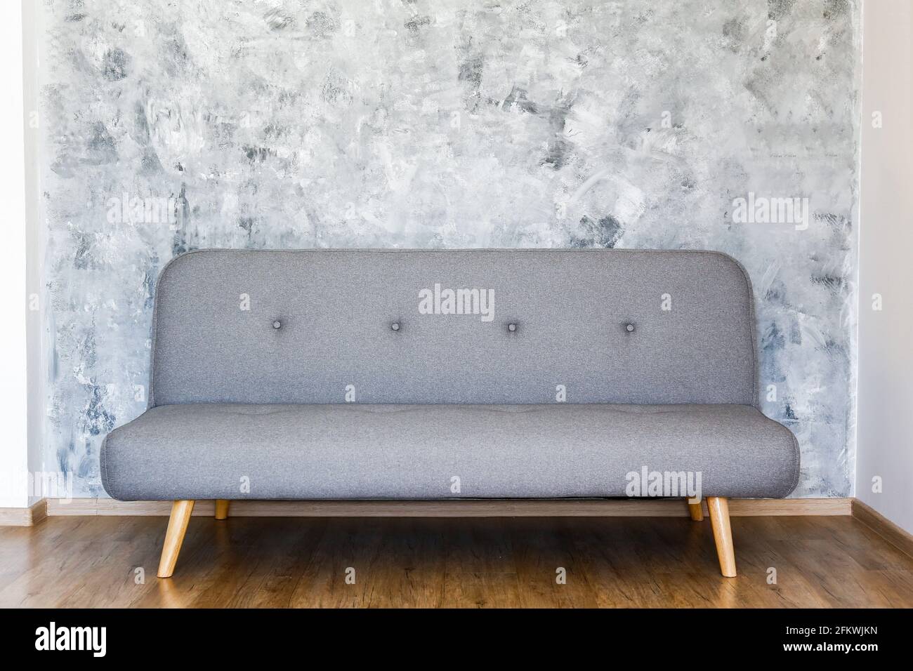 Minimalistic interior design concept. Grey textile sofa in spacious room of loft style apartment with wood textured laminated flooring. Background, co Stock Photo