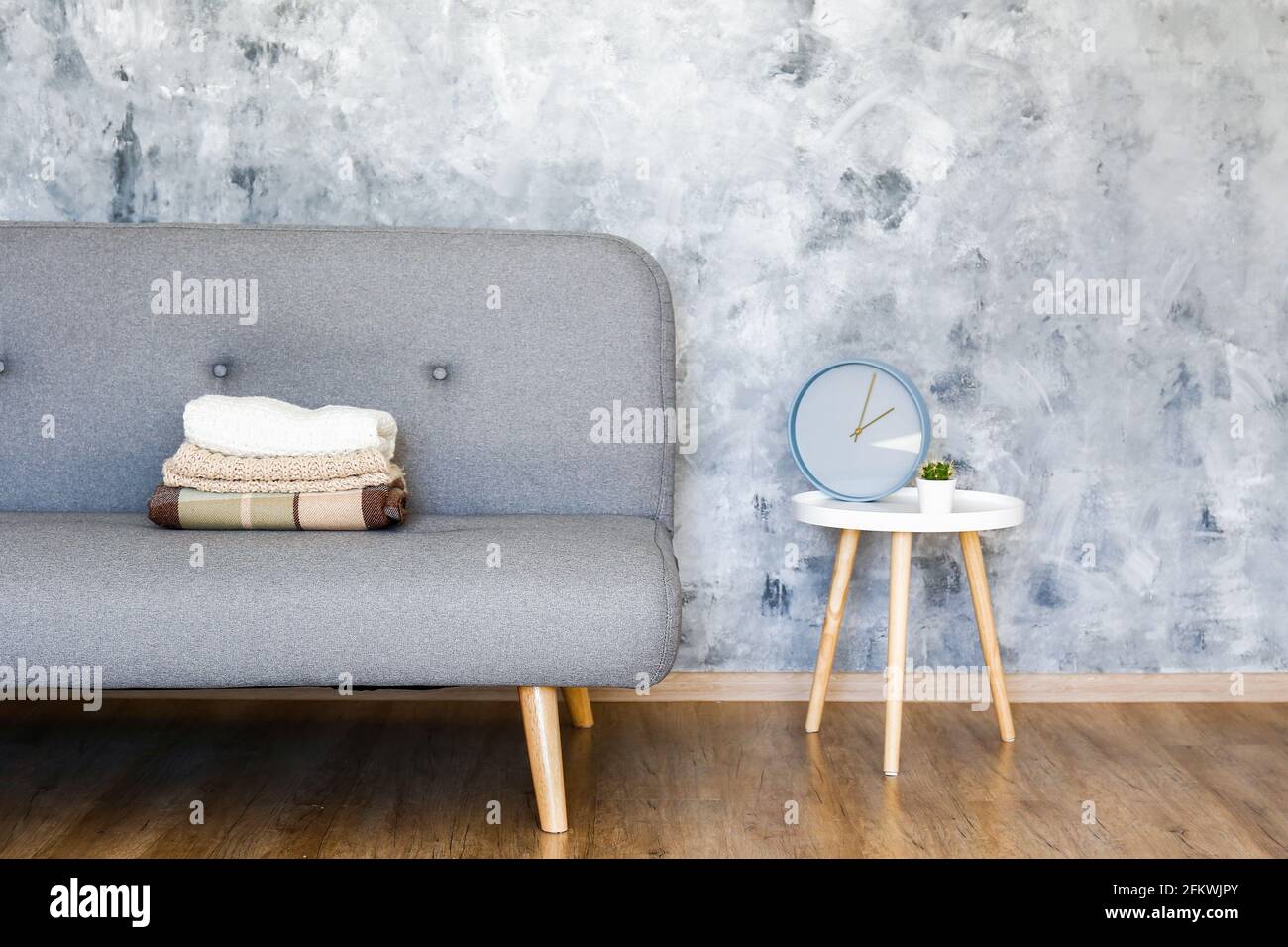 Minimalistic interior design concept. Grey textile sofa in spacious room of loft style apartment with wood textured laminated flooring. Background, co Stock Photo