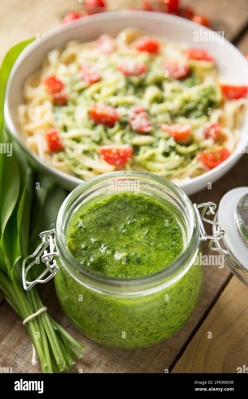 Pesto made from wild garlic, Allium ursinum, that includes rapeseed oil, lemon juice and pine nuts in a glass jar. It has been used to make a linguine Stock Photo