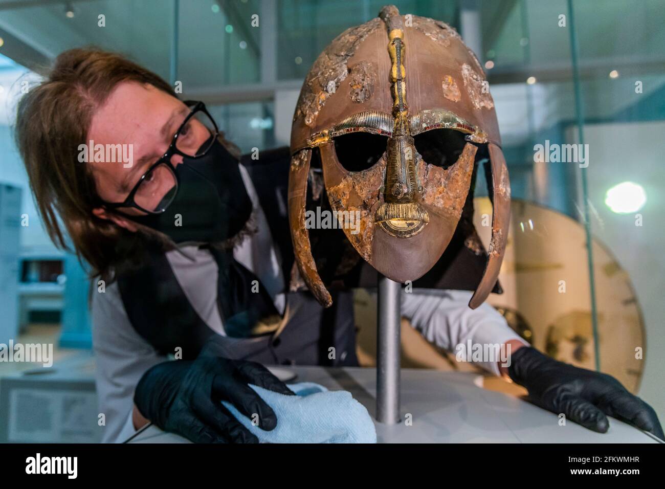 London, UK. 4th May, 2021. Jim Peters, Collection Manager: Care and Access, with the iconic ornate iron helmet - The treasures from Sutton Hoo at the British Museum. They featured in the blockbuster film The Dig Starring Ralph Fiennes and Carey Mulligan, have not been seen by the public since the Museum first closed in March 2020 due to the Coronavirus pandemic. Credit: Guy Bell/Alamy Live News Stock Photo