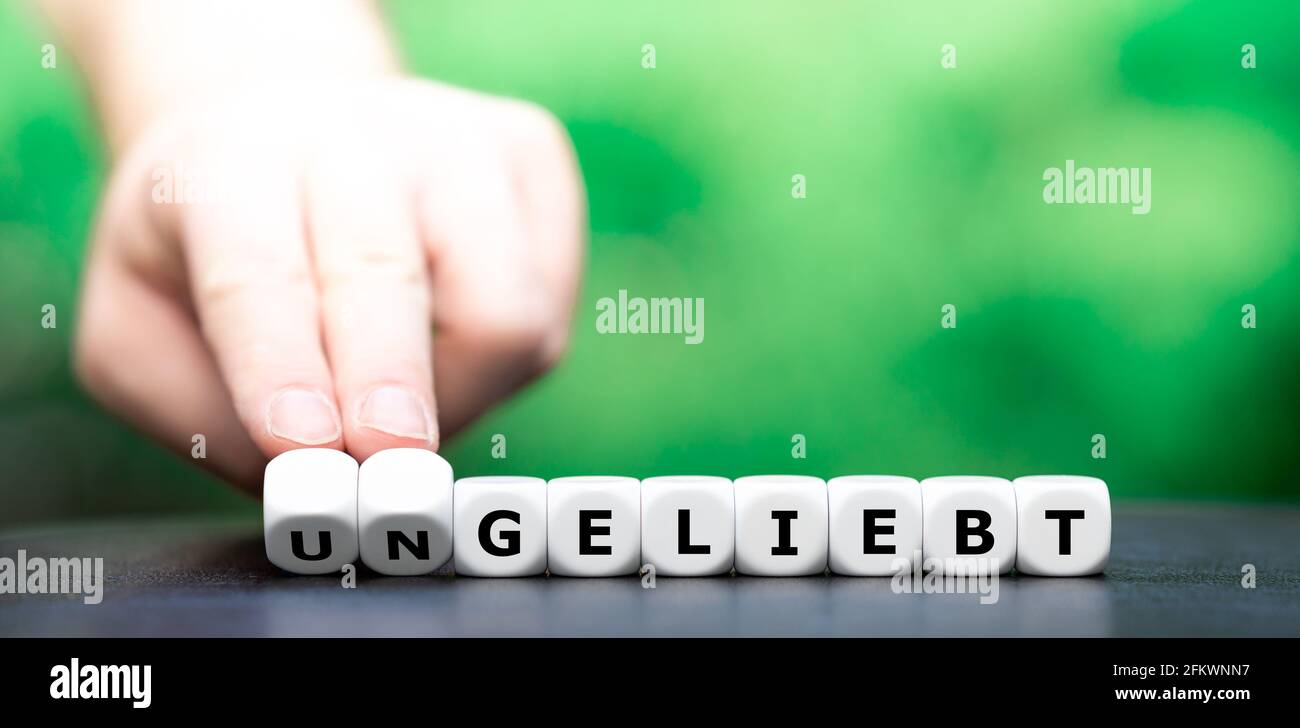 Hand turns dice and changes the German word "ungeliebt" (unloved) to