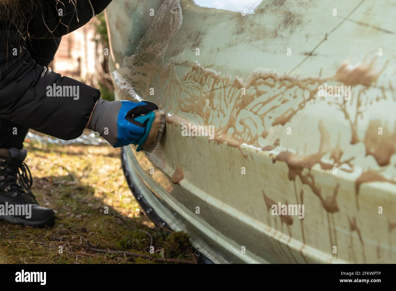 Close up of hand with gloves scrubbing dirt of the boat surface outside. Sailboat maintenance. Stock Photo