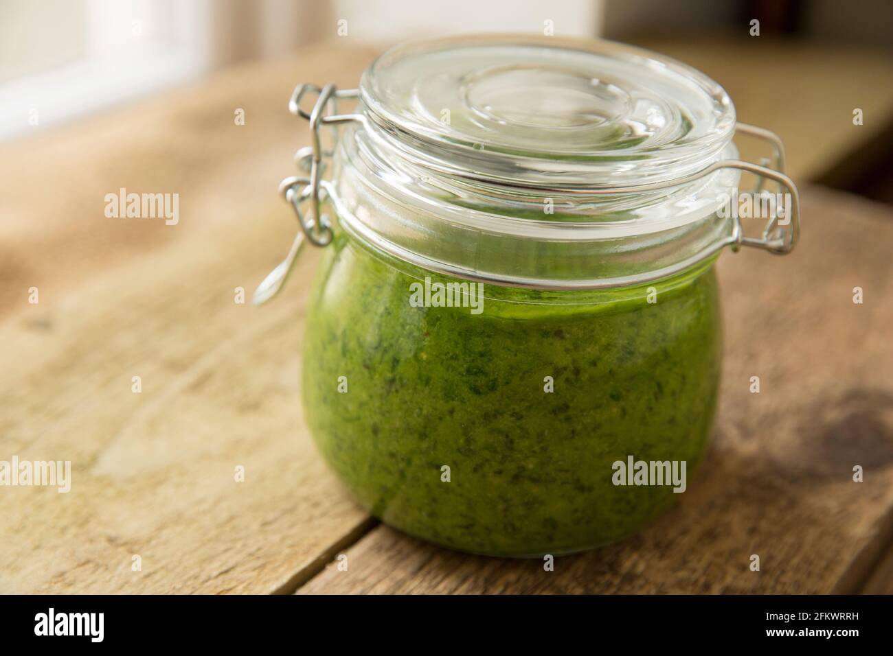 Pesto made from wild garlic, Allium ursinum, that includes rapeseed oil, lemon juice and pine nuts. It is seen here in a glass jar after being mixed i Stock Photo
