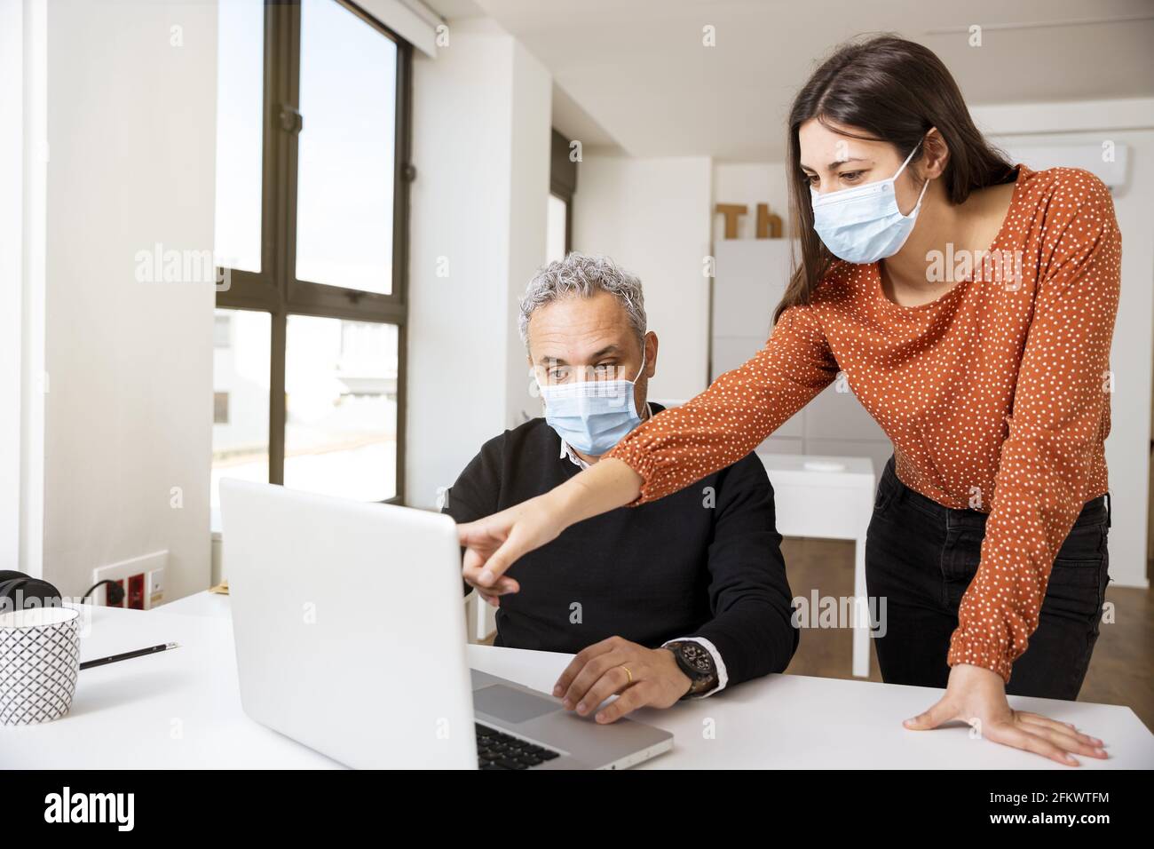 Business colleagues wearing masks while working on laptop - business ...