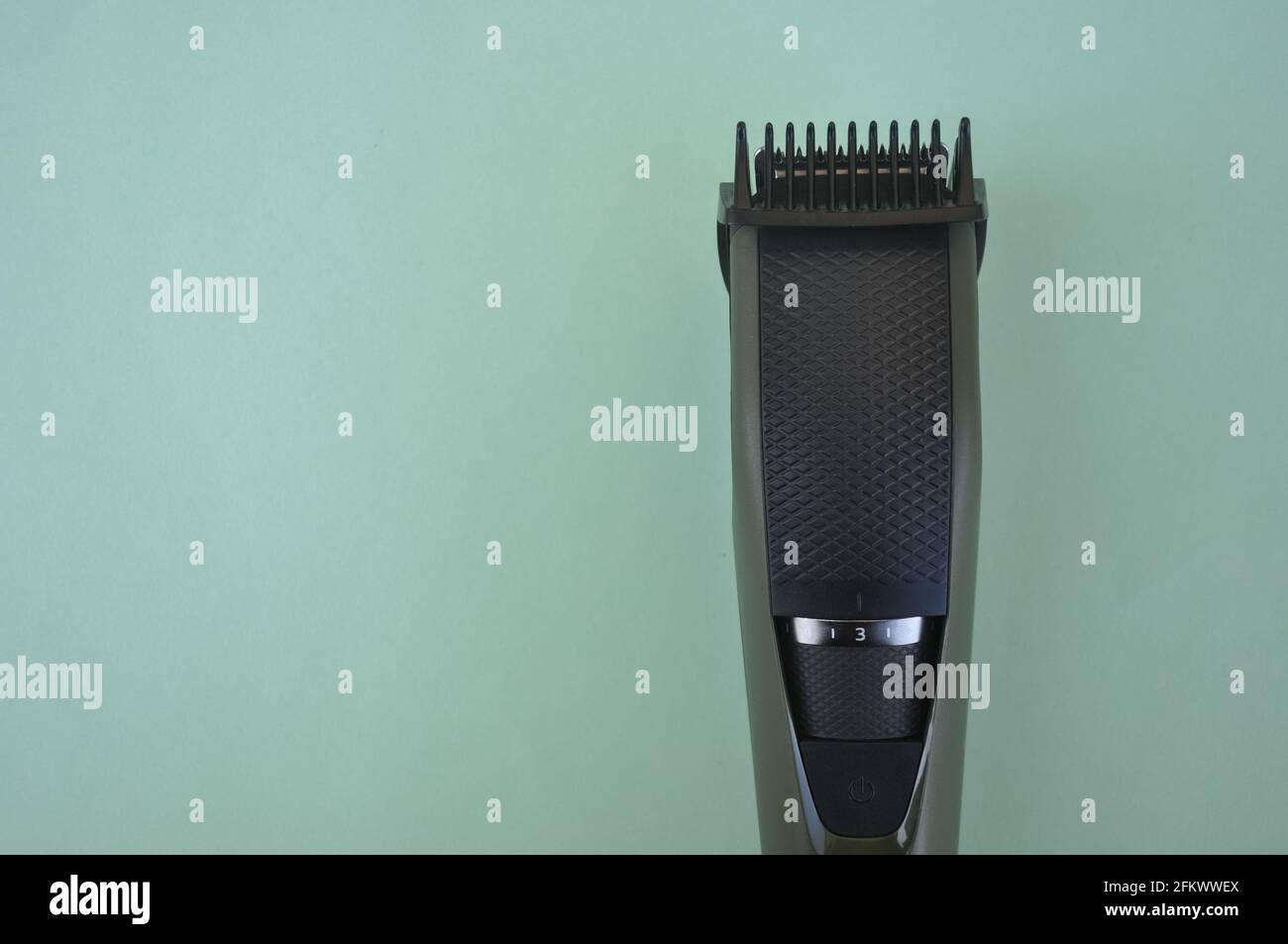 Top angle of front view of beard trimmer with attached comb with negative space, Trimmer isolated over green background. Stock Photo