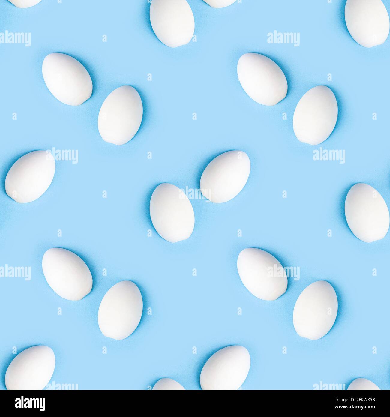 Two white wooden eggs seamless pattern on bright light blue background. Stock Photo