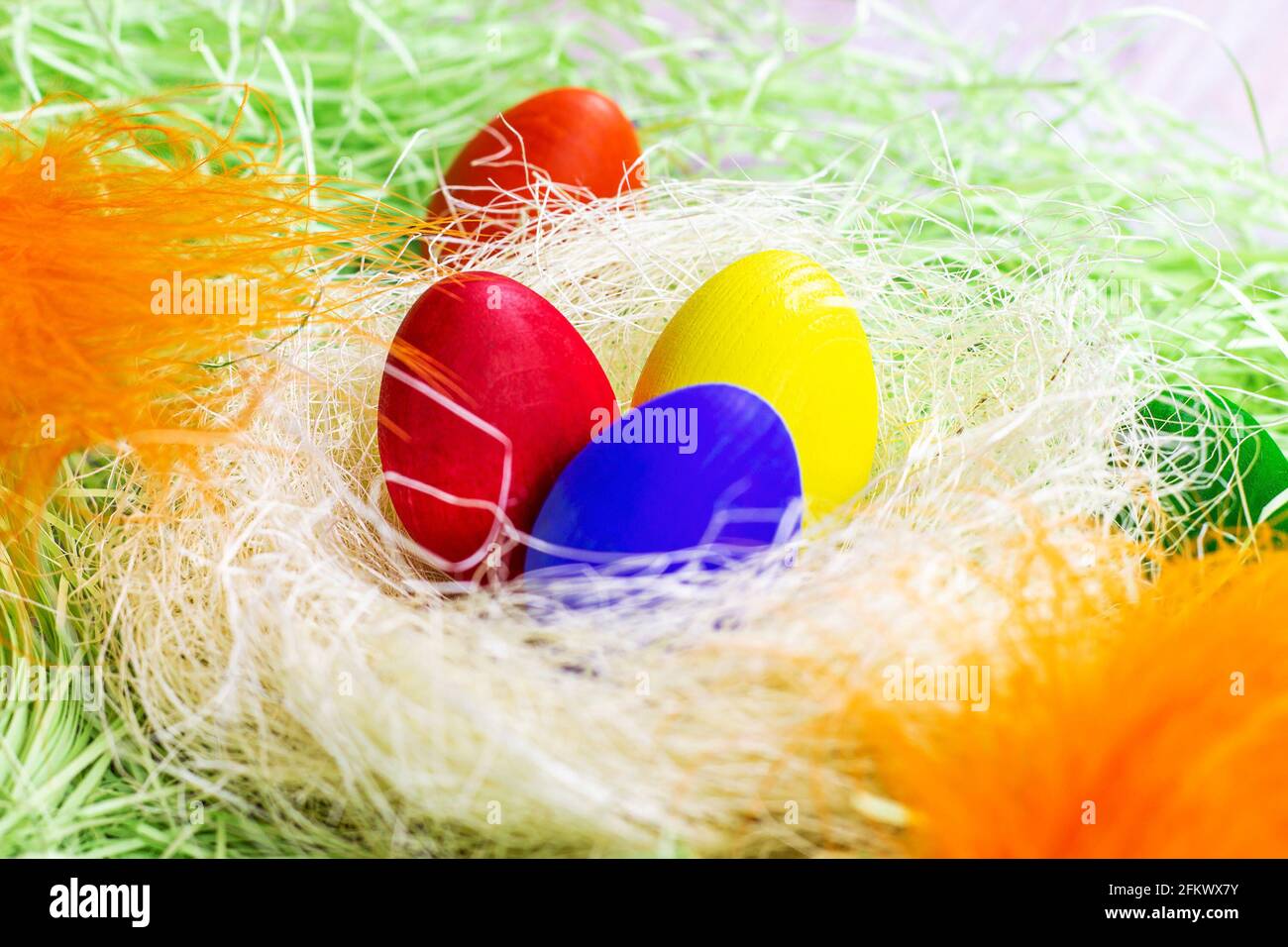 Colorful painted Easter eggs decorations in the nest on light green background. Stock Photo