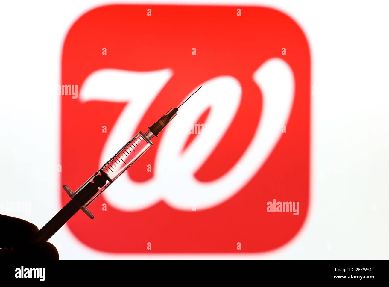 In this photo illustration a medical syringe is seen in front of a logo