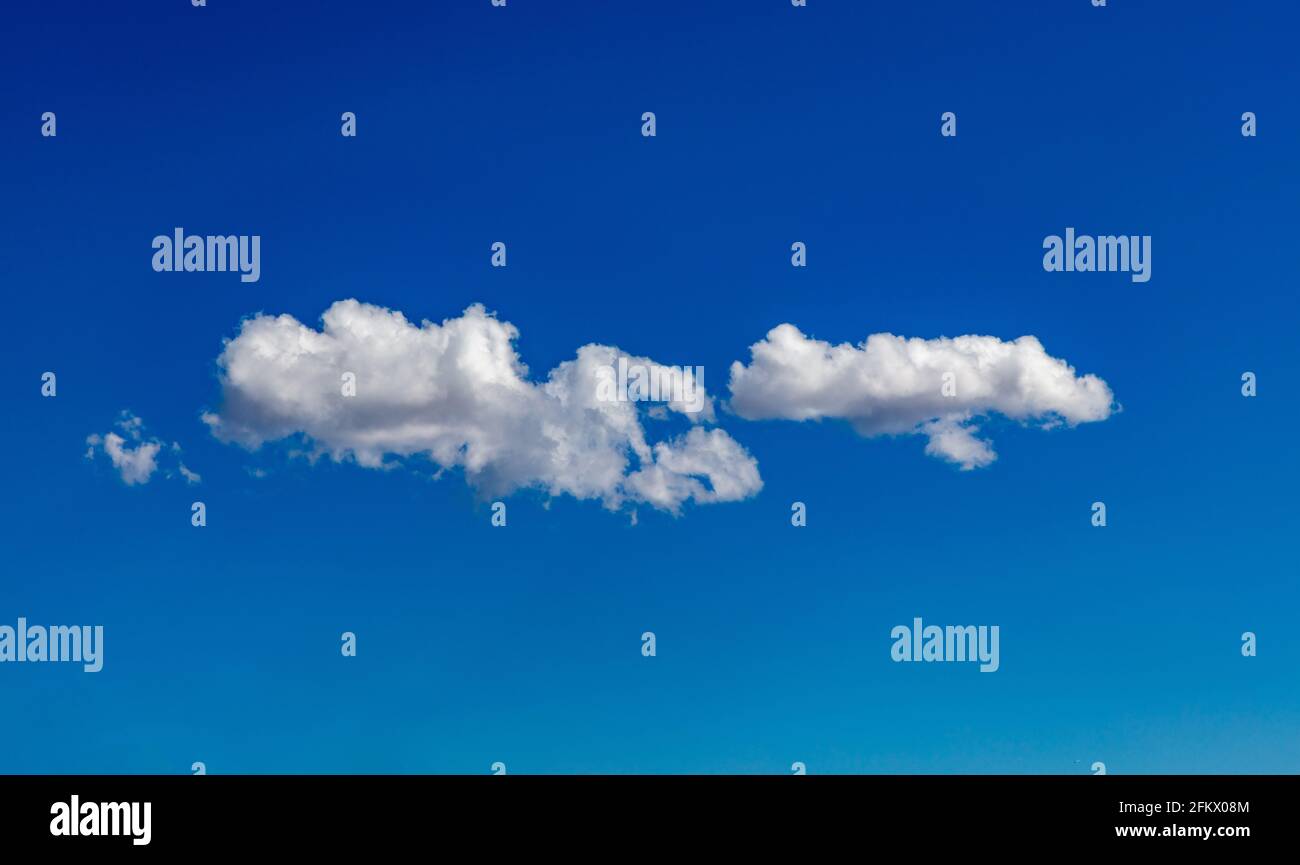 Cloudscape white on blue sky. Fluffy cumulus clouds isolated on clear sky background, sunny spring day. Stock Photo