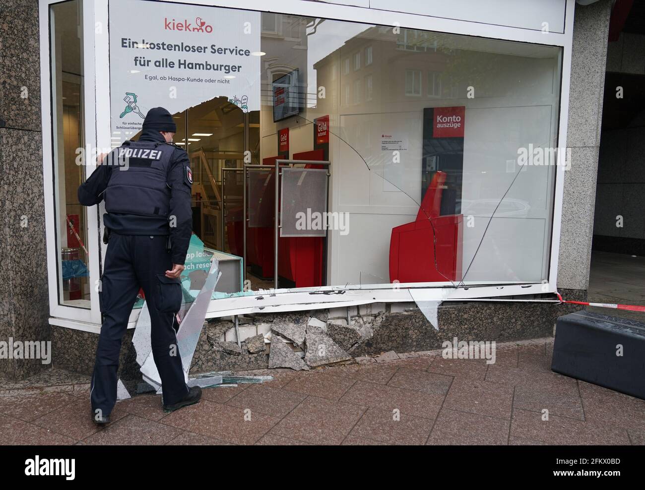 Hamburg, Germany. 04th May, 2021. A policeman stands in front of the window of a Haspa branch that was destroyed in an accident. In Waitzstraße in Hamburg, which is known for numerous 'shop window accidents', a car has once again crashed into the window of a shop. On Tuesday, a 73-year-old woman lost control of her car and crashed it into the building housing the Hamburg savings bank Haspa, a police spokesman told the Deutsche Presse-Agentur in Hamburg. Credit: Marcus Brandt/dpa/Alamy Live News Stock Photo