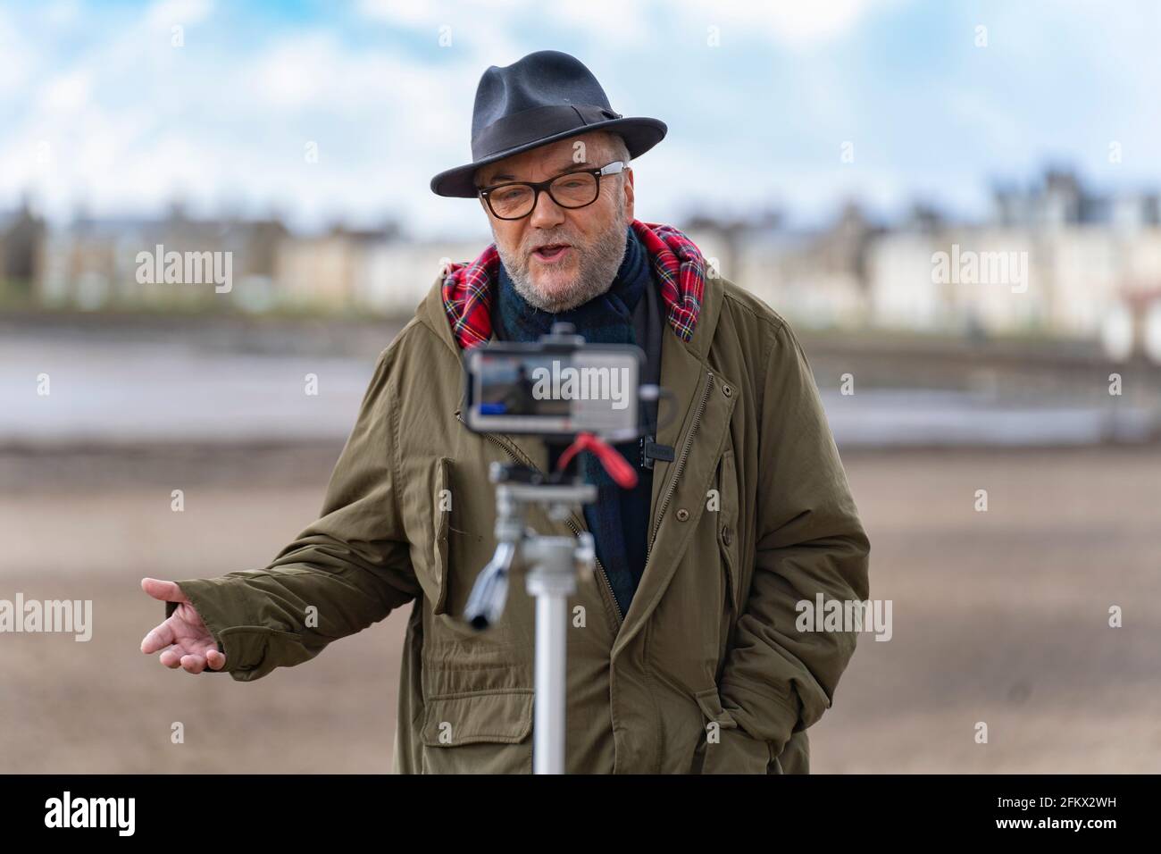 Troon, Scotland, UK. 4 May 2021. Founder of  pro Union All for Unity party George Galloway campaigns on the beach promenade in Troon in Ayrshire. Galloway made a live streamed speech and met with supporters and members of the public. He had lunch of fish and chips at The Wee Hurrie takeaway restaurant beside Troon harbour. Iain Masterton/Alamy Live News Stock Photo