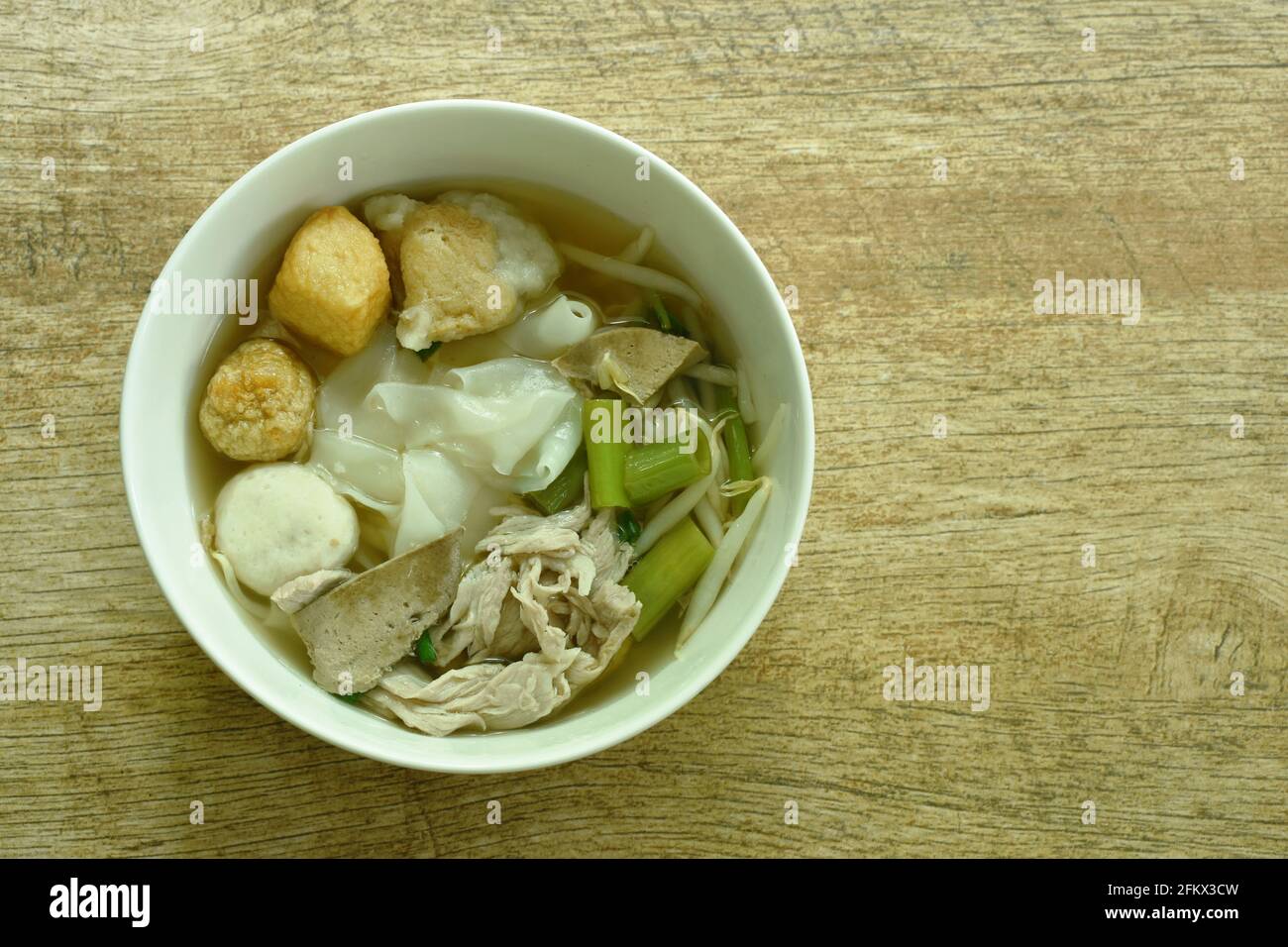 large rice noodles topping slice boiled pork and ball in soup on bowl