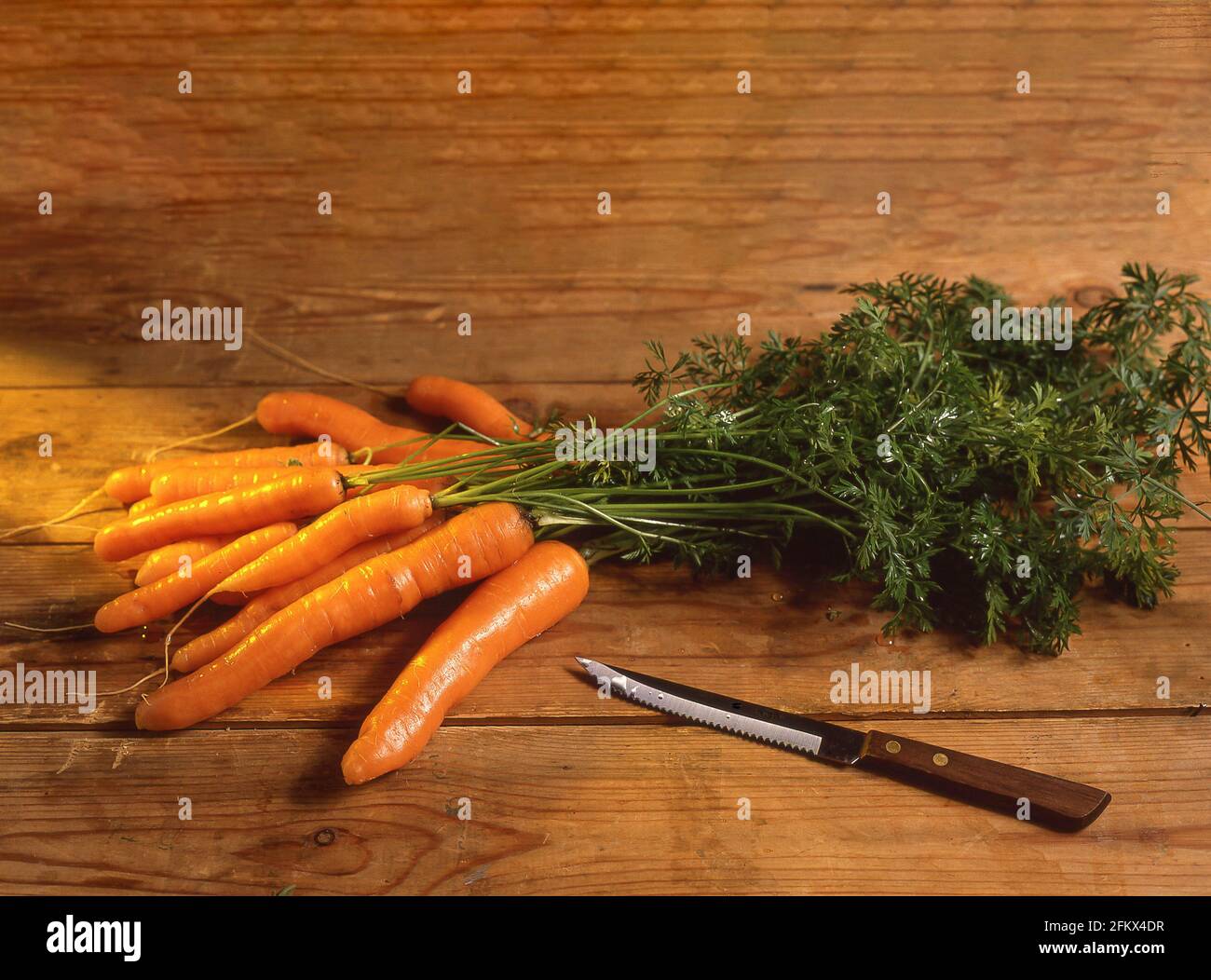 Carrots with stalks on chopping block, Berkshire, England, United Kingdom Stock Photo