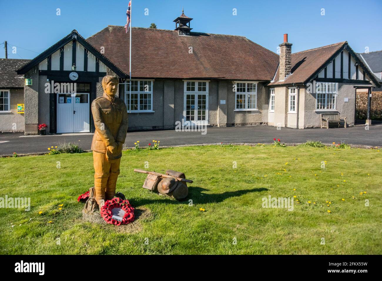 War Memorial Soldier, carved from in-situ tree stump, and War Memorial Institute, Ashford-in-the-Water, Derbyshire Stock Photo
