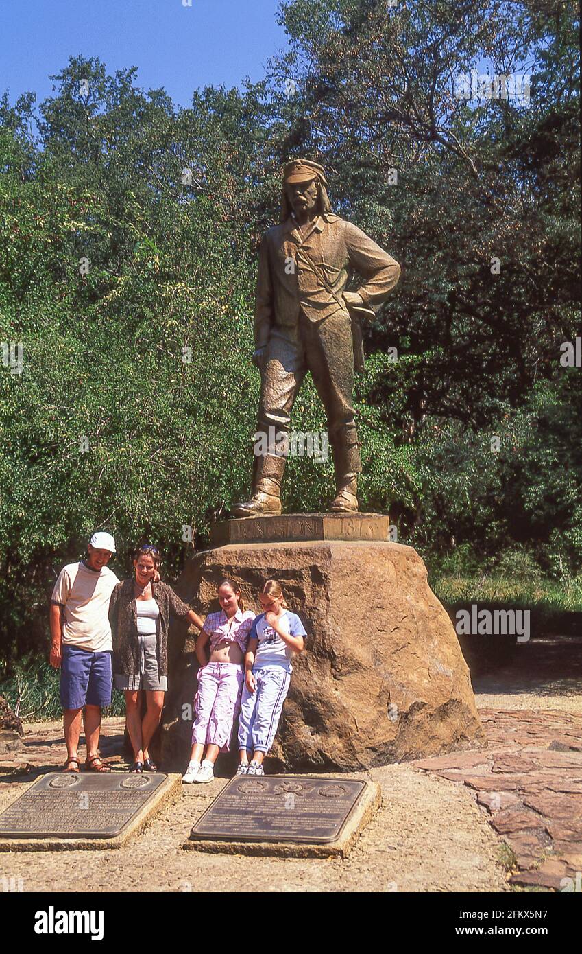 Family posing by The David Livingston (Victorian explorer) memorial statue at Victoria falls, Victoria Falls, Matabeleland, Zimbabwe Stock Photo