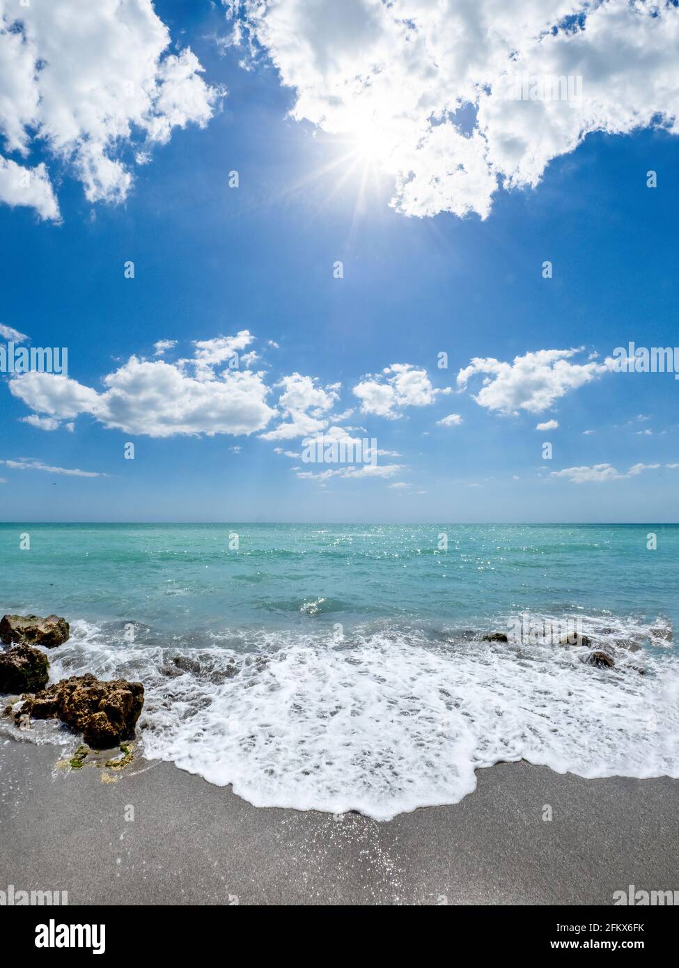 Small waves breaking amoung rocks on the shore of the Gilf of Mexico at Caspersen Beach with blue sky and white clouds in Venice Florida USA Stock Photo
