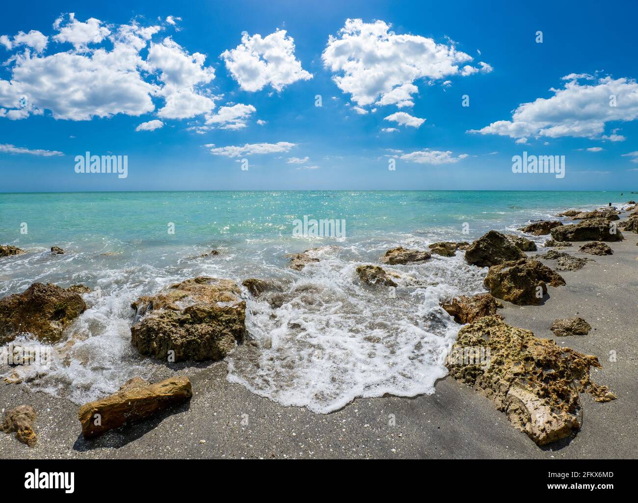 Small waves breaking amoung rocks on the shore of the Gilf of Mexico at Caspersen Beach with blue sky and white clouds in Venice Florida USA Stock Photo