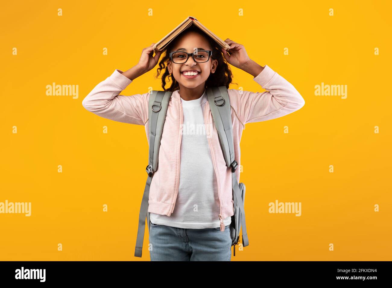 Smiling black girl holding open book on her head Stock Photo - Alamy