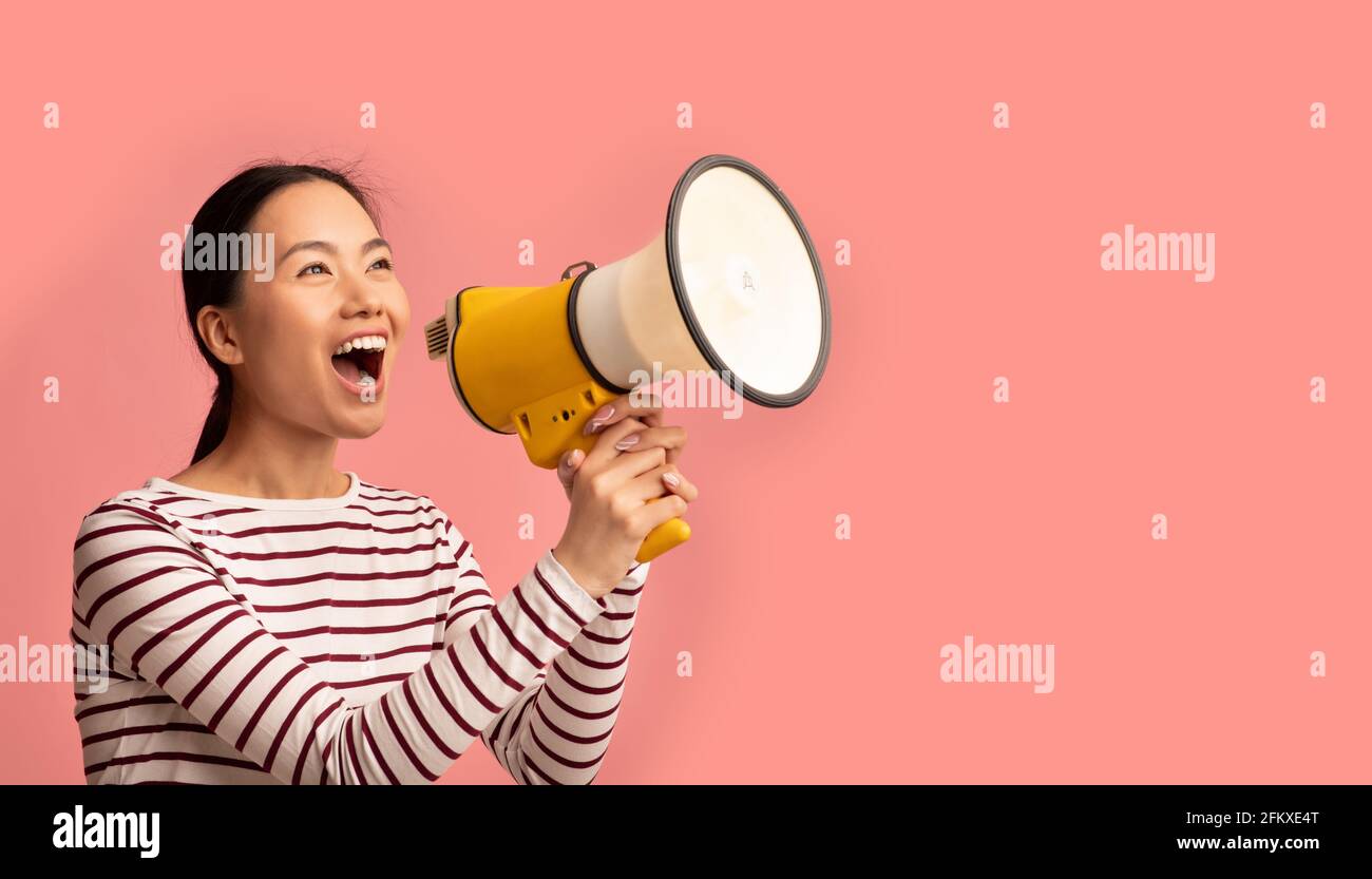 Announcement. Young Asian Lady With Megaphone In Hands Shouting At Copy Space Stock Photo