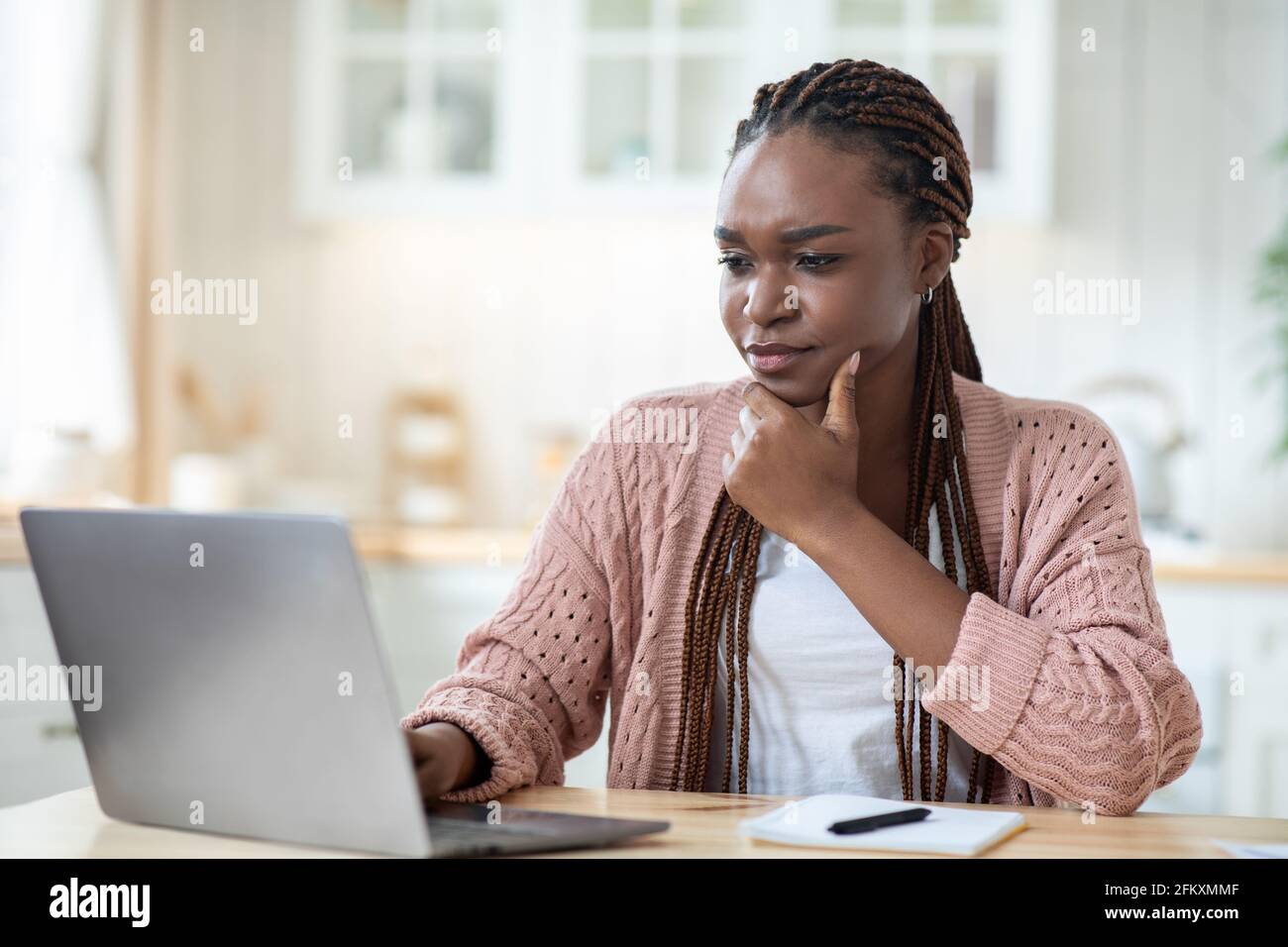 Stressed black freelancer woman looking at laptop screen while working at home Stock Photo