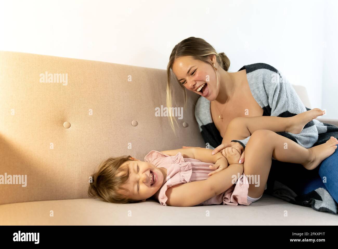 mom and daughter playing and loving each other on the sofa at home Stock Photo
