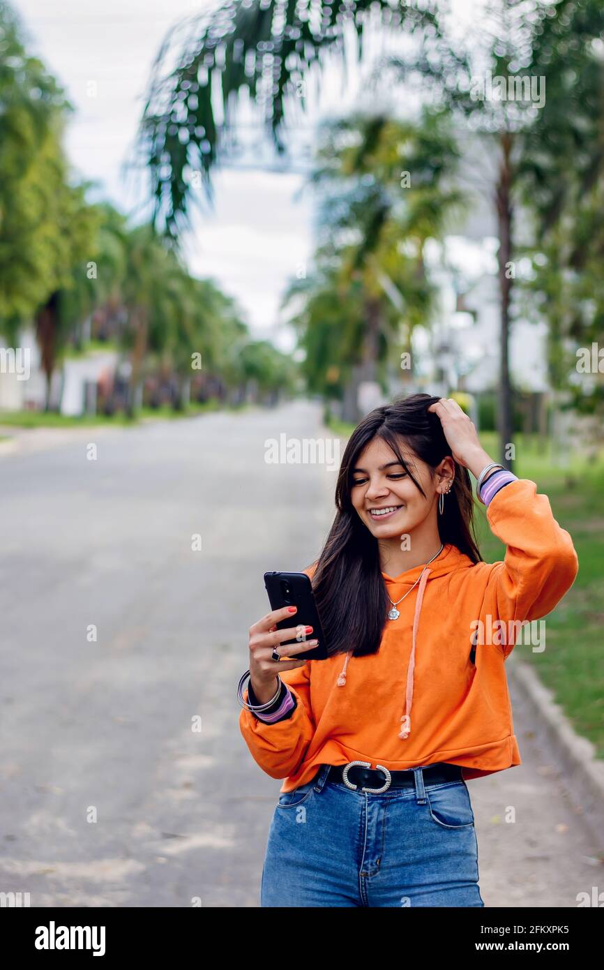 Happy hispanic teen girl looking at smart phone Stock Photo - Alamy