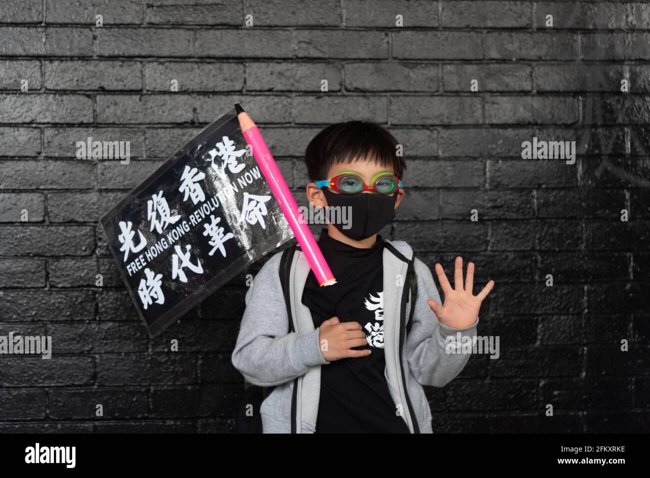 Hong Kong, China, 12 Jan 2020, A child makes the sign 'five demands' after his father dressed him up like a protester, during a pro-democracy rally. Stock Photo