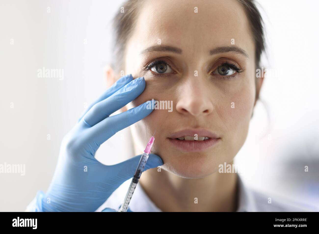 Doctor gives woman an injection into nasolabial fold. Stock Photo