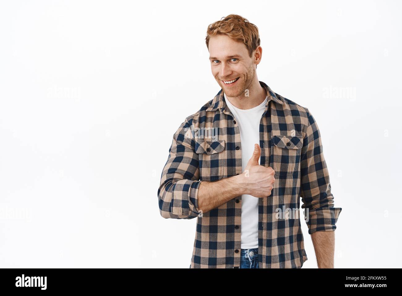Well done, very good. Handsome smiling man with red hair, showing thumbs up to praise and compliment great work, give approval, say yes, no problem Stock Photo