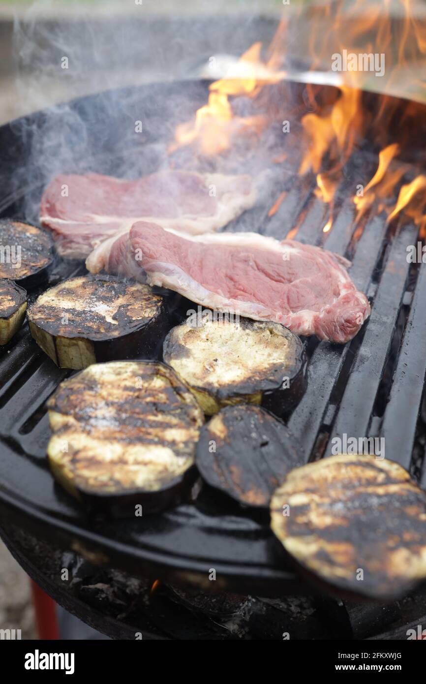 Process of making barbecue with meat fillets and vegetables on a grill ...