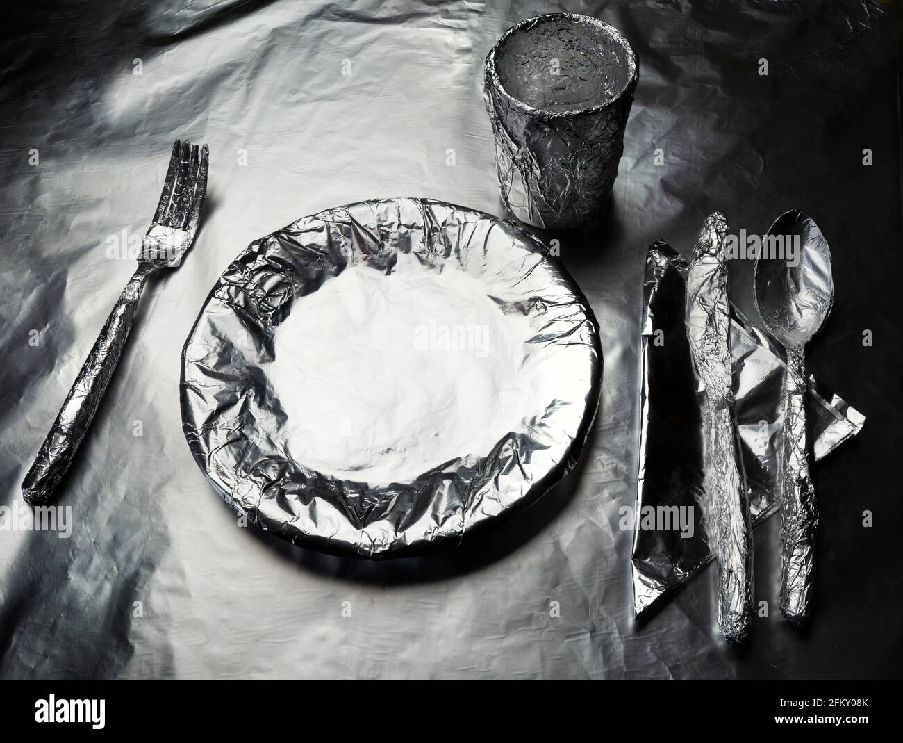 home plate, crockery and a glass covered with aluminum foil Stock Photo