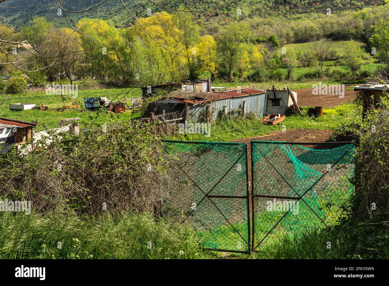 Metal shacks, used as a storage room for country tools, in the vegetable gardens fenced with a gate. Abruzzo, Italy, Europe Stock Photo