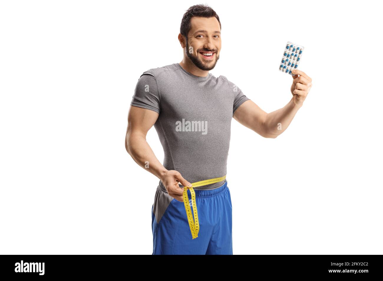 Young man measuring his waist and holding diet pills isolated on white background Stock Photo