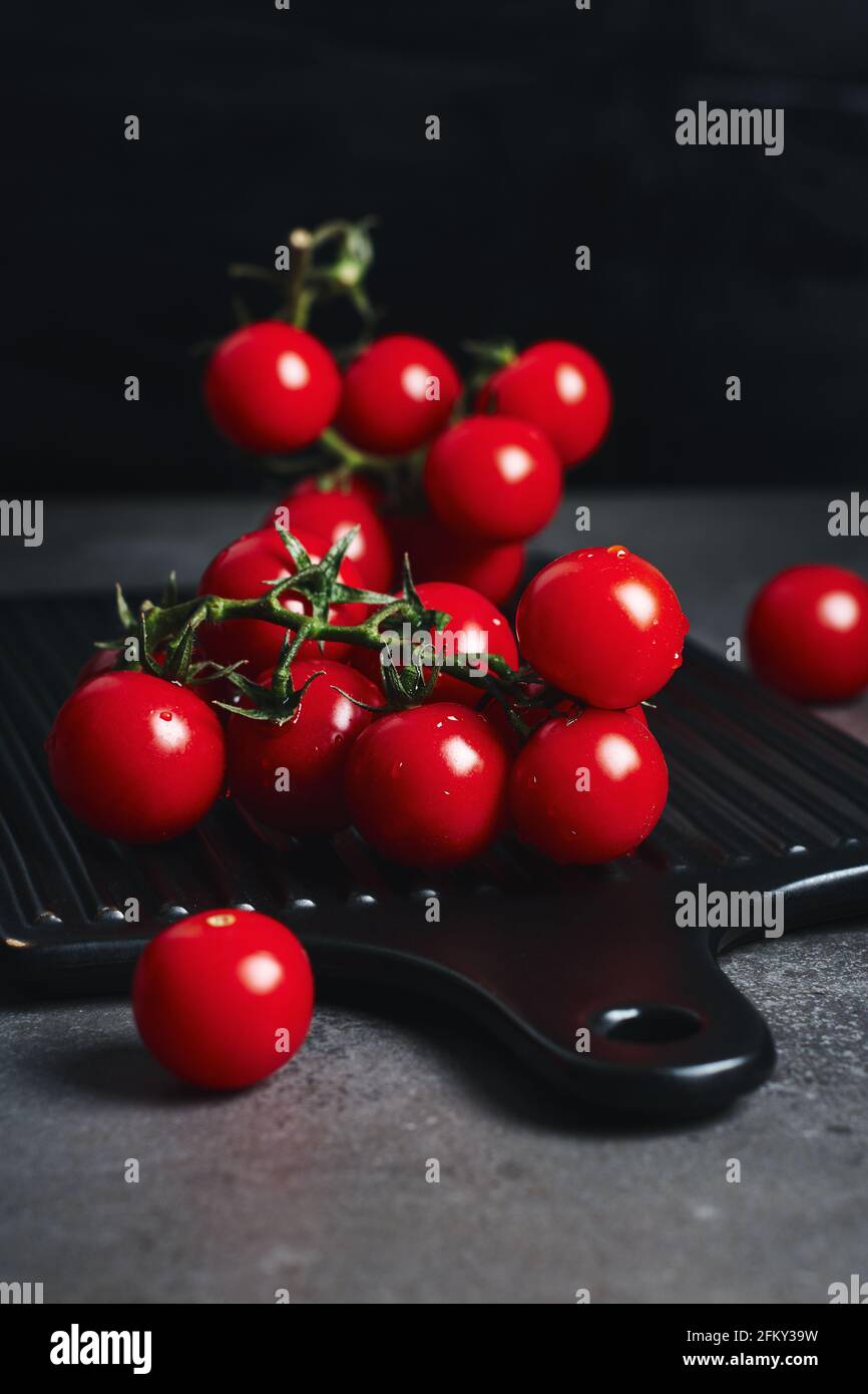 Fresh red cherry tomatoes on the vine. Dark background Stock Photo - Alamy